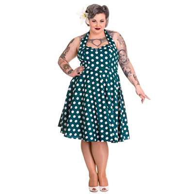 Mujer con vestido pin up estilo años 50 en tallas grande. El vestido es verde aguacon lunares grandes blancos.