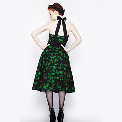 Mujer pin up de espaldas que le encantan los vestidos pin up rockabilly. Por eso, lleva un vestido años 50 en color verde.